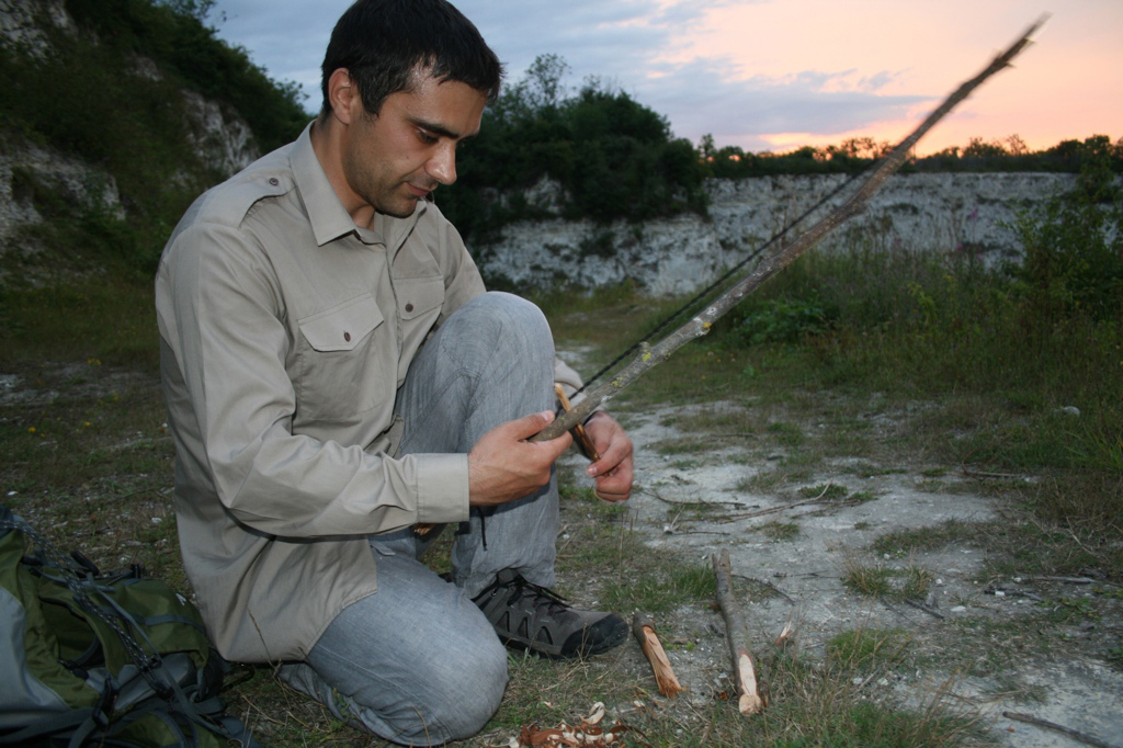 Leigh Robinson working on a bow-drill set outdoors